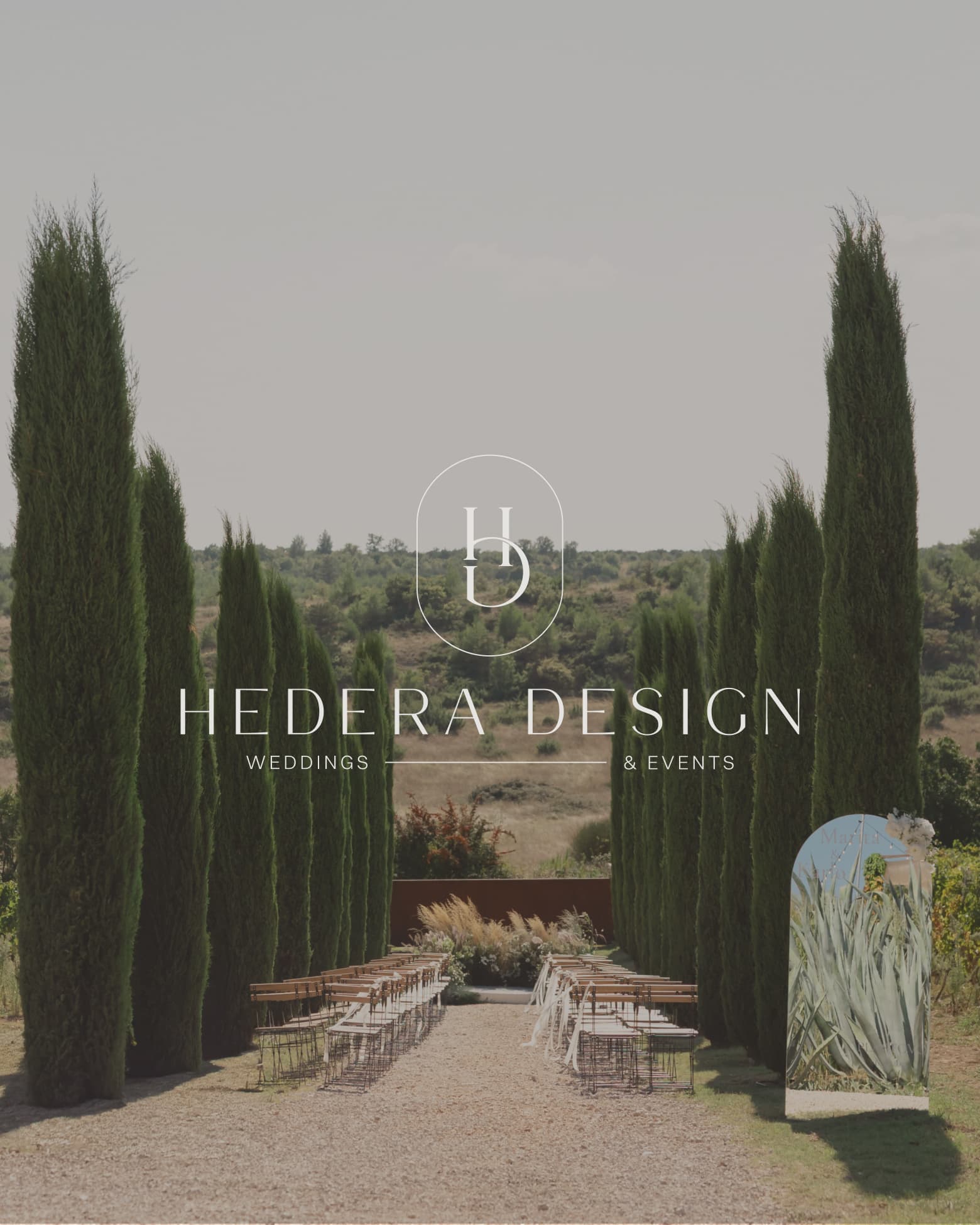 Hedera Design logo mark set against a cypress-lined wedding aisle